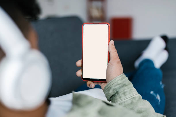 istock Young man lying on the sofa and holding phone with blank screen 1388653204