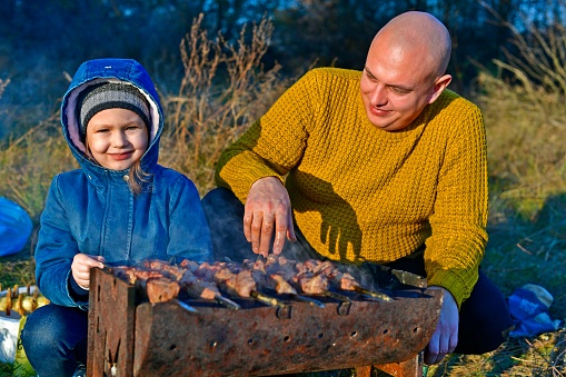 Child girl in late autumn with parents at a picnic.