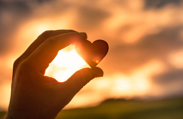 istock Man holding heart against sunset sky 1388654488