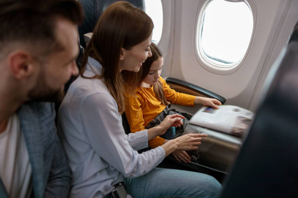 istock Parents and daughter reading magazine in airplane 1388655156