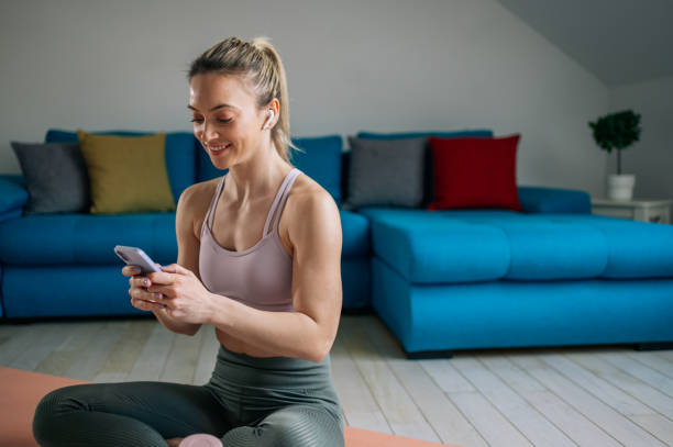 istock Woman using airpods and a smartphone while training at home 1388666919