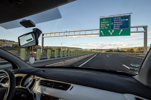 Picture of a roadsign on the Motorway Avtocesta A1 between Ljubljana and Koper, at a junction, seen from the interior of a car driving fast