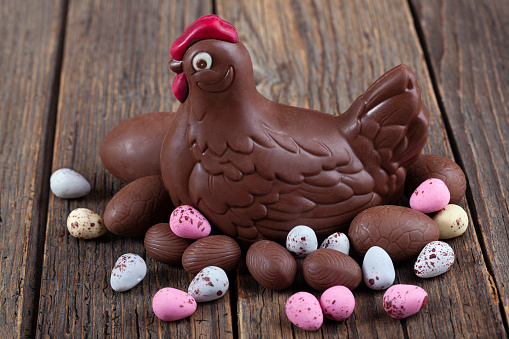 Easter chocolate chicken and eggs over a white rustic wooden table