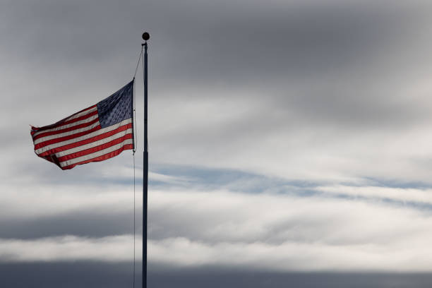 A slightly lowered flag in front of gray clouds.
