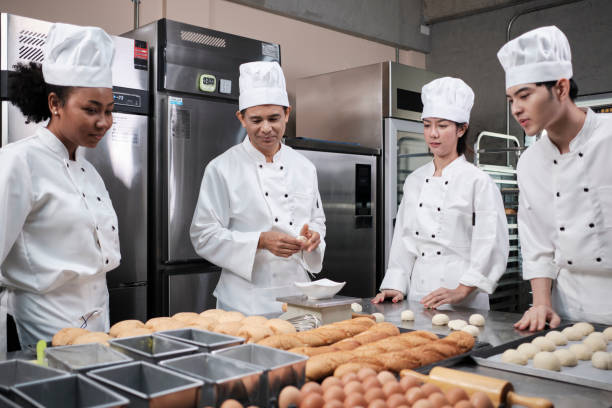 istock Chefs team in uniforms prepare to bake bread and pastry in stainless kitchen. 1388683339