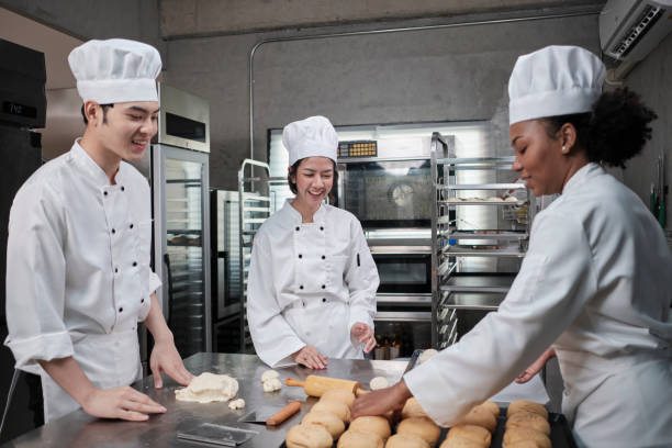 istock Chefs team in uniforms prepare to bake bread and pastry in stainless kitchen. 1388683377