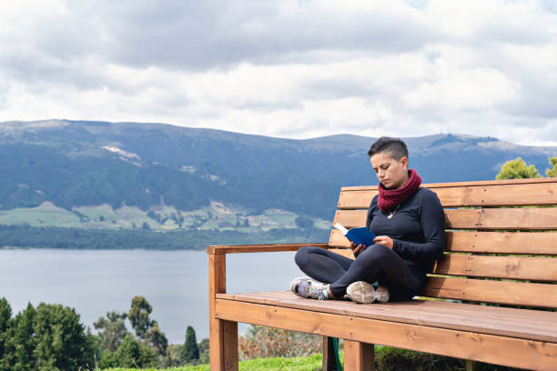 istock Relaxed young woman in a chair reading a book. 1388689222