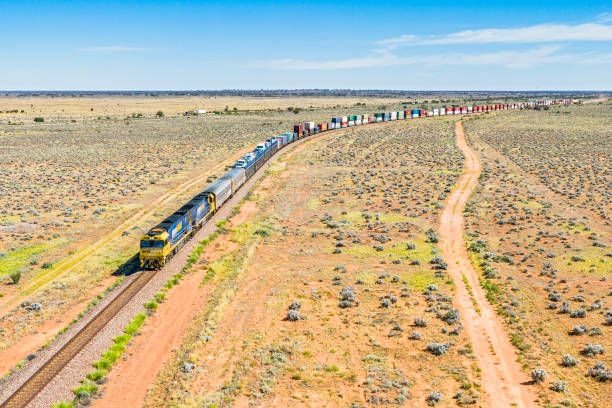 luftaufnahme pacific national intermodaler containerzug, der durch flache wüstenlandschaften im norden südaustraliens fährt. - land vehicle rail freight locomotive australia stock-fotos und bilder