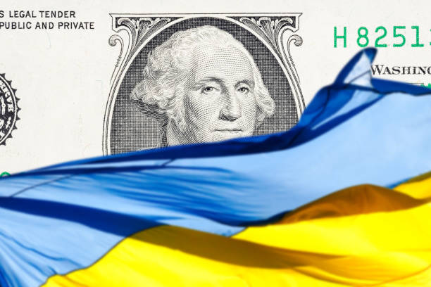 ukrainian national flag on foreground and US one hundred dollars paper currency on background. ukraine investment concept stock photo