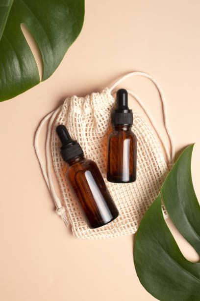 istock Dropper bottles on beige background with monstera palm leaf. Blank aromatic oil container design, medical packaging template. Herbal cosmetic concept. Flat lay, top view 1388699969