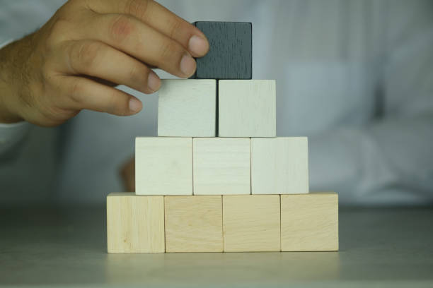 istock Businessman put building pyramid of blank cubes on table. Space for text and icon 1388702286