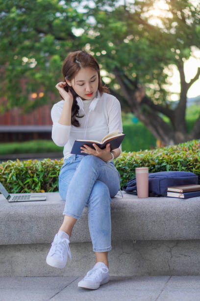 istock Cute young Asian female student working on a laptop computer outdoors, studying concepts, working in the public domain. 1388708846