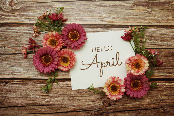 istock Hello April typography text with flowers on wooden background 1388710043