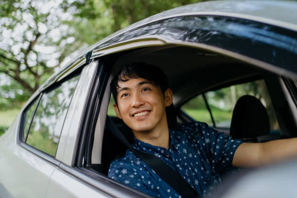Young asian man driving a car Image of an Asian Chinese driver sitting in car and driving happy car asian stock pictures, royalty-free photos & images