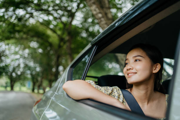 Young woman enjoying road trip Image of an Asian Chinese woman travelling in car back seat and look out from car window happy car asian stock pictures, royalty-free photos & images