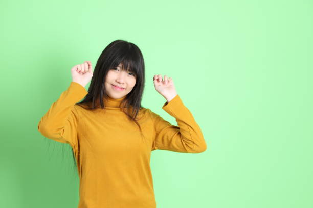 The cute young Asian girl with casual dressed standing on the green background