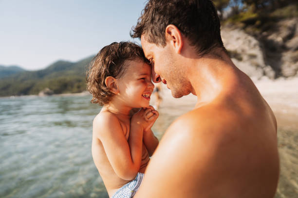 Father and son on sunset beach. Dad and son playing together outdoors on a summer beach.