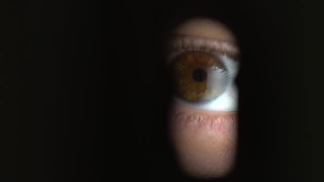 Human eye looking through a keyhole