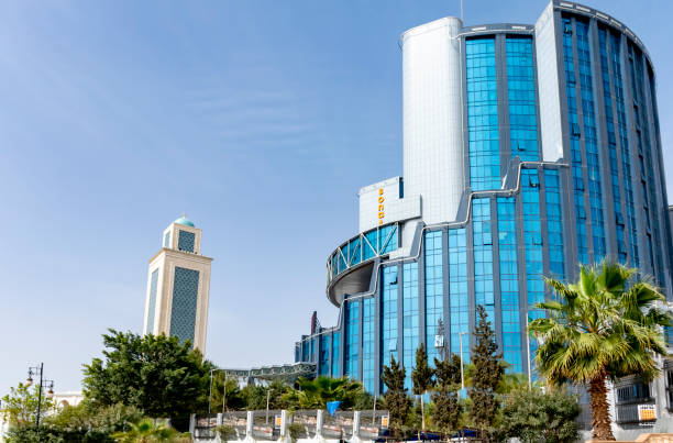 Sonatrach AVAL building and Ibn Badis minaret mosque. Cite Djamel, Oran- Mars 21, 2022: headquarters of the Sonatrach company, a low angle view of the modern buildings, trees, palm trees and blue sky. oran algeria photos stock pictures, royalty-free photos & images