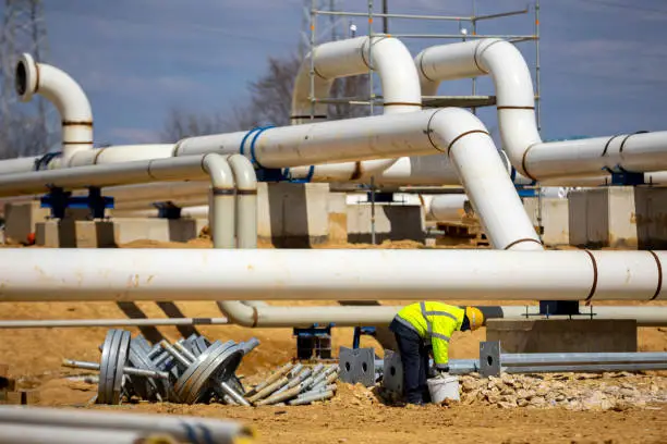 Worker works on a construction site of an interconnected natural gas transmission pipeline. Highly integrated network that moves natural gas. Connection point between the transmission company and the receiving party.