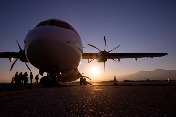 Silhouette of an airplane near the track at an airport suring the evening sunset. People boarding on the aircraft.