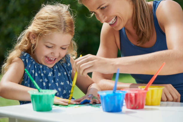 foto de una madre y su hija pintando juntas afuera - togetherness learning playful mother fotografías e imágenes de stock