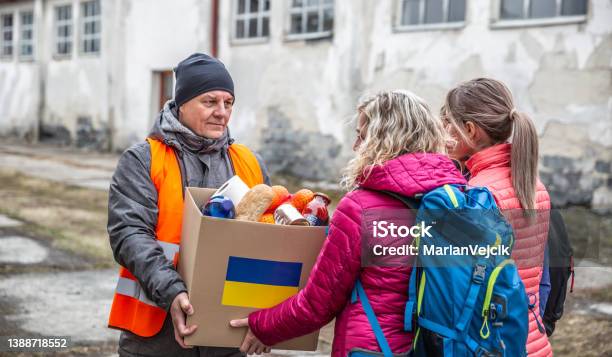 Volunteer In Orange West Gives A Box Of Food Donation To Fleeing Refugees From Ukraine Stock Photo - Download Image Now