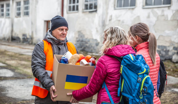 wolontariusz w pomarańczowym zachodzie przekazuje pudełko z darami żywnościowymi uciekającym uchodźcom z ukrainy. - humanitarian aid zdjęcia i obrazy z banku zdjęć