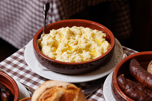 Traditional side dish of the Balkans and Mediterranean served on ethnic restaurant table, mashed potato in rustic pottery, other specialties on buffet