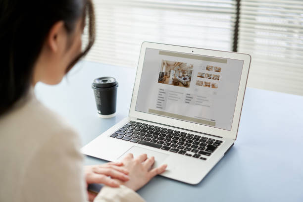 asian women viewing real estate websites on a computer - huis interieur fotos stockfoto's en -beelden
