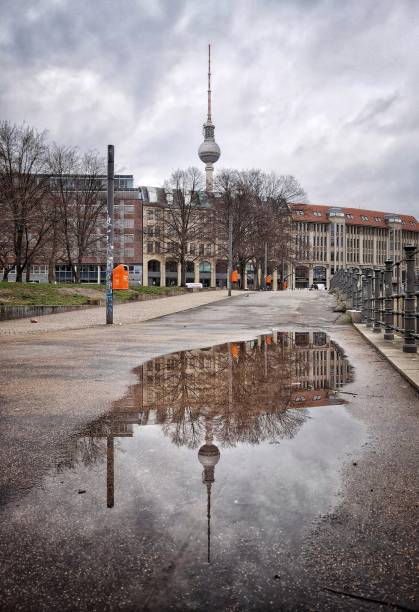 February 26, 2022 - Berlin, Germany: A puddle with the reflection of the Berlin Fernsehturm (tv-tower) at James-Simon-Park in a cloudy and rainny day