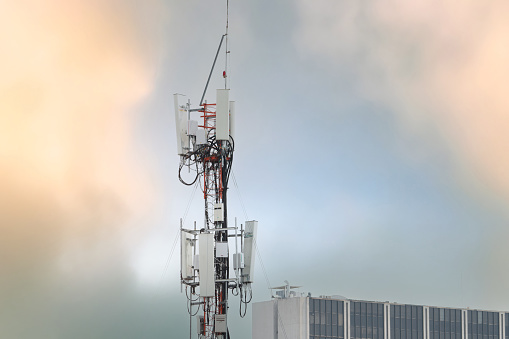 Telecommunication tower near building. Antenna. Radio and satellite pole on gray sky. Communication technology. Telecommunication industry. Mobile or telecom 4g network. Telecommunication industry.