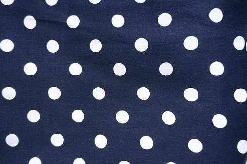 Texture of dark blue cotton fabric with white polka dot pattern