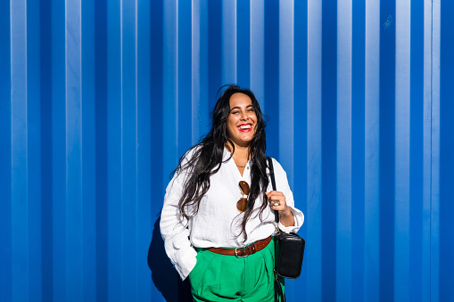 The shot of a stylish Maori woman with stylish outfit isolated against blue background.