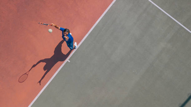 point de vue drone joueur de tennis asiatique servant la balle avec ombre directement au-dessus - tennis photos et images de collection