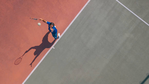 ドローン視点 アジアのテニス選手 真上に影のあるボールをサービング - tennis serving men court ストックフォトと画像
