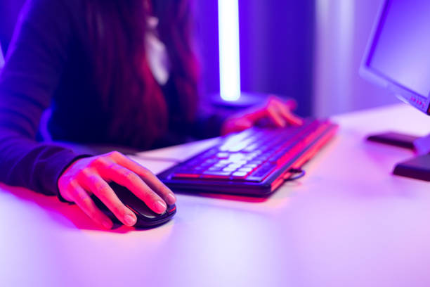 istock Professional streamer. Close up hand woman holding mouse control playing video game on computer pc in living room. Female Streaming playing game online in dark room neon light 1388729672