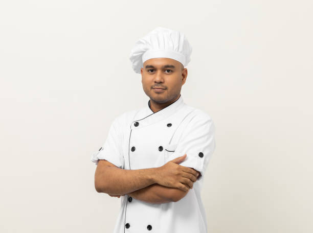 istock Smiling Young handsome asian man chef in uniform with hat standing posting looking at camera on isolated white background. Cooking man Occupation chef or baker People in kitchen restaurant and hotel. 1388730300