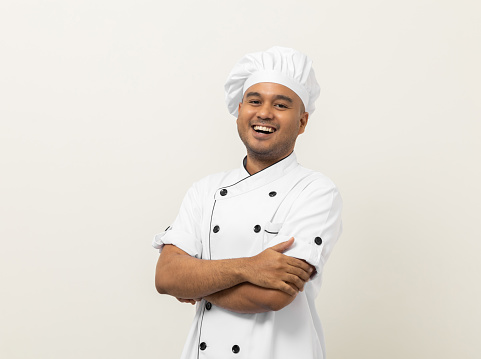 Smiling Young handsome asian man chef in uniform with hat standing posting looking at camera on isolated white background. Cooking man Occupation chef or baker People in kitchen restaurant and hotel.