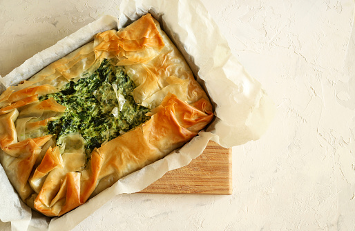 Traditional greek cuisine. Homemade Spanakopita, phyllo pastry pie with spinach and feta cheese on white background. Directly above.