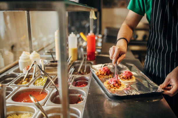 Chef preparing tacos One man, male chef making tacos in fast food restaurant. fast food uniform stock pictures, royalty-free photos & images