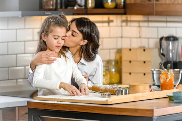 istock Mother and little daughter baking together in a home kitchen making a pie 1388733984