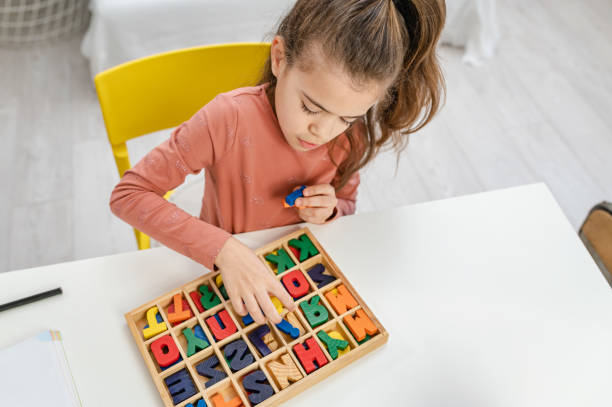Little schoolgirl playing with wooden letters