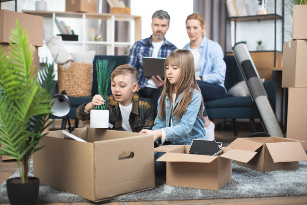 istock Parents sitting on sofa with laptop, while kids playing and unpacking boxes at new flat 1388741412