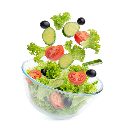salad of green lettuce, tomatoes, cucumbers, olives. Vegetables fall into the salad bowl. view from above.