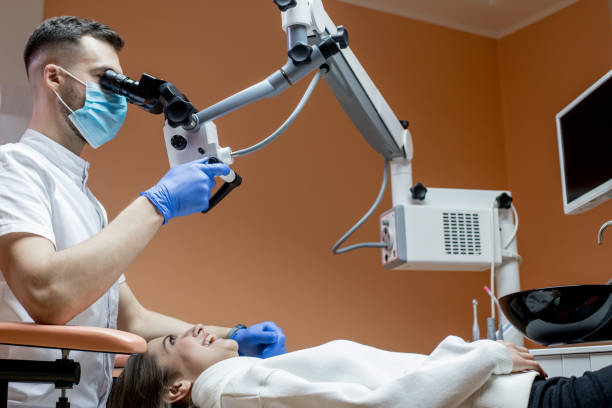 istock Dentist looking through a microscope at the patient's teeth. Modern progressive dentistry. 1388752221