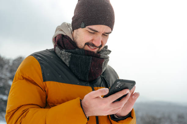 istock Young man in snowy winter forest using cell phone 1388752252