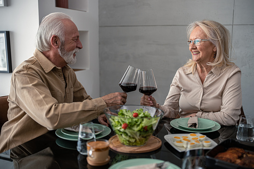 Happy senior couple eating together for Easter and enjoying wine