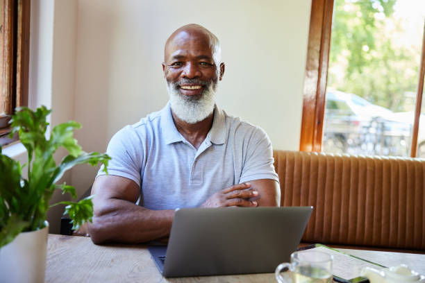 istock Smiling mature man working on a laptop while sitting in a cafe 1388752802