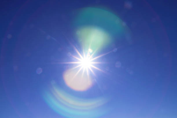 Rainbow arcs glare from the bright sun on the blue sky. Beautiful background to illustrate celestial phenomena, aura, high vibrations, the universe